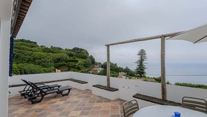 Un patio con tavolo e sedie, un ombrellone e vista sul mare.