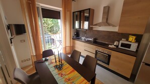 Cocina compacta con zona de comedor, microondas y ventana con cortinas.