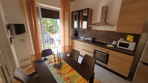 A compact kitchen with a dining area, a microwave, and a window with curtains. - Il Fiorino di Santa Croce, 5 minutes from Santa Croce (Firenze)