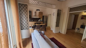A modern living room with a sofa, a dining area with chairs, and a kitchen in the background. - Il Fiorino di Santa Croce, 5 minutes from Santa Croce (Firenze)