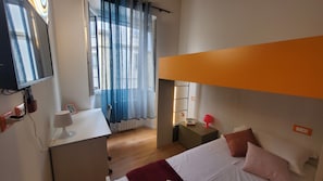 A bedroom with a bunk bed, a desk with a lamp, a chair, a window with curtains, and a bedside table with a lamp. - Il Fiorino di Santa Croce, 5 minutes from Santa Croce (Firenze)