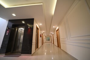 Passadís modern d'hotel amb sòl brillant, portes de fusta i façana negra a un costat.