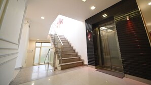 Ein modernes Interieur mit einer Treppe zum zweiten Stock, einer Glastür als Eingang und einem dunklen Aufzug.