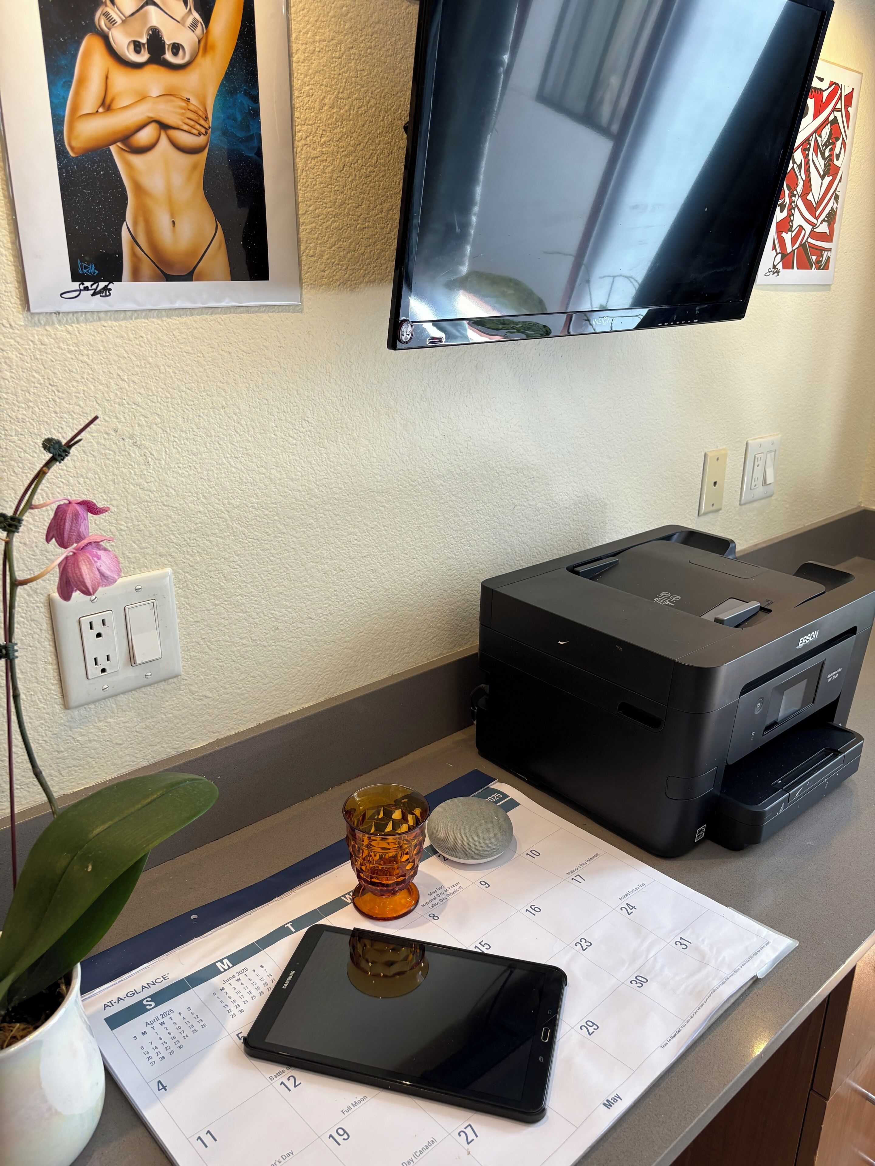 Een bureau met een tablet, een printer, een plant in pot en een agenda.