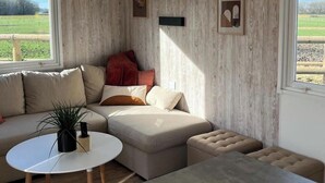 Uma sala de estar aconchegante com um sofá seccional, uma mesa de centro redonda e um pequeno banquinho.