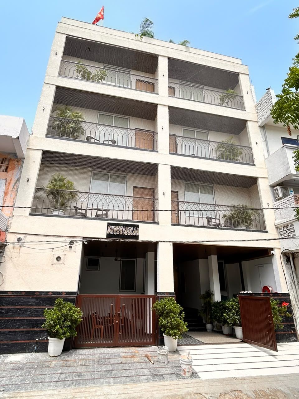 A multi-story building with balconies, a gated entrance, and potted plants.