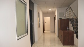 Ein Korridor mit Marmorboden, einem Holzschrank und einer Treppe mit Metallgeländern.