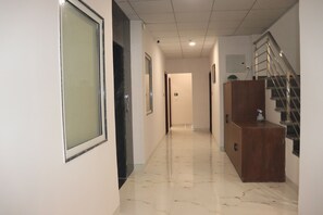 A corridor with a marble floor, a wooden cabinet, and a staircase with metal railings. - SHREE LEELAA HOTEL (Jaipur)