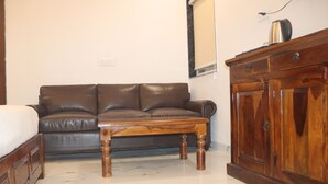 Ein Zimmer mit einem braunen Ledersofa, einem Holztisch und einem Holzschrank.