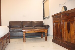 A room with a brown leather sofa, a wooden table, and a wooden cabinet. - SHREE LEELAA HOTEL (Jaipur)