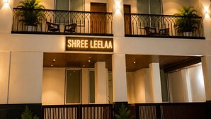 Ein mehrstöckiges Hotel mit Balkonen, Blumentöpfen und einem Schild mit der Aufschrift 'SHREE LEELAA'.