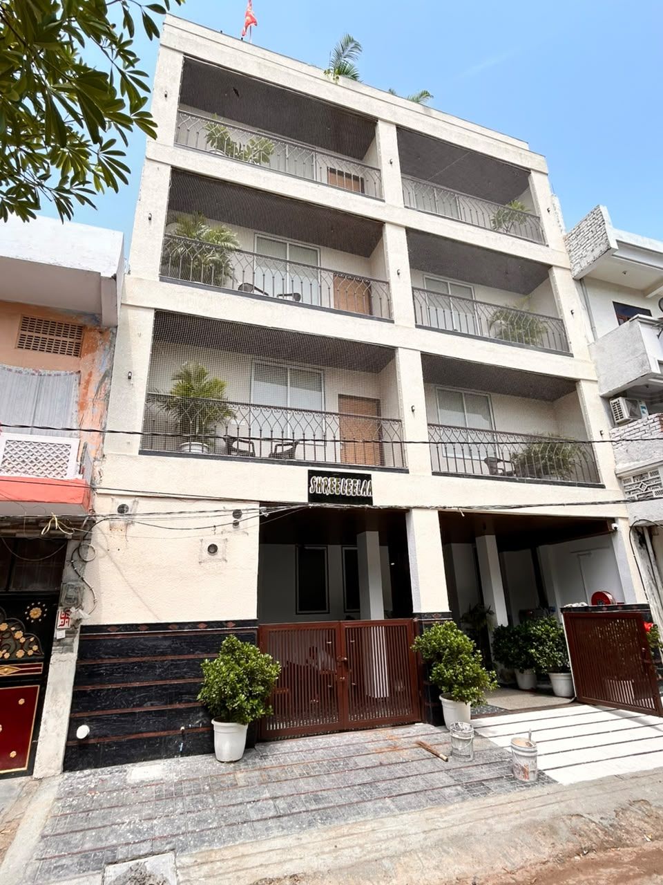 A multi-story building with balconies, a gated entrance, and potted plants.