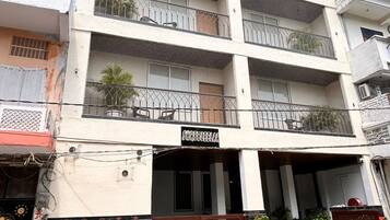 A multi-story building with balconies, a gated entrance, and potted plants.