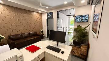 A modern office with a desk, computer, and a brown leather couch.