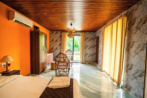 A hotel room with a bed, a desk, a chair, and a view of the outdoors.