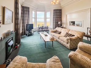 A spacious living room with a fireplace, a television, a dining area, and a view of the outdoors.