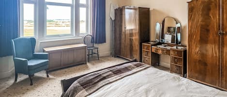 A bedroom with a bed, a desk, a chair, a dresser, and a wardrobe.
