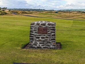 Um monumento de pedra com uma placa em um campo de golfe.
