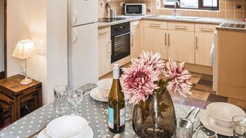 A kitchen with wooden cabinets, a microwave, and a dining table set with plates, glasses, and cutlery.