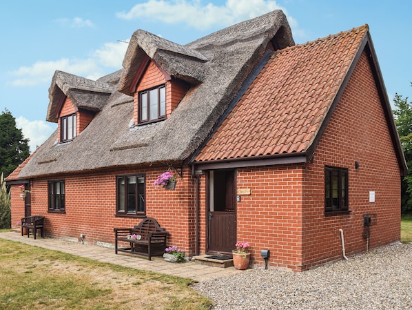 A two-story brick house with a steeply pitched roof, a front porch with a bench, and a mailbox. - Cherry Tree Cottage - UK52225 (Horning)