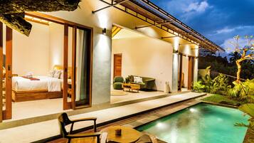 A modern outdoor living area with a pool, a bed, and a seating area.