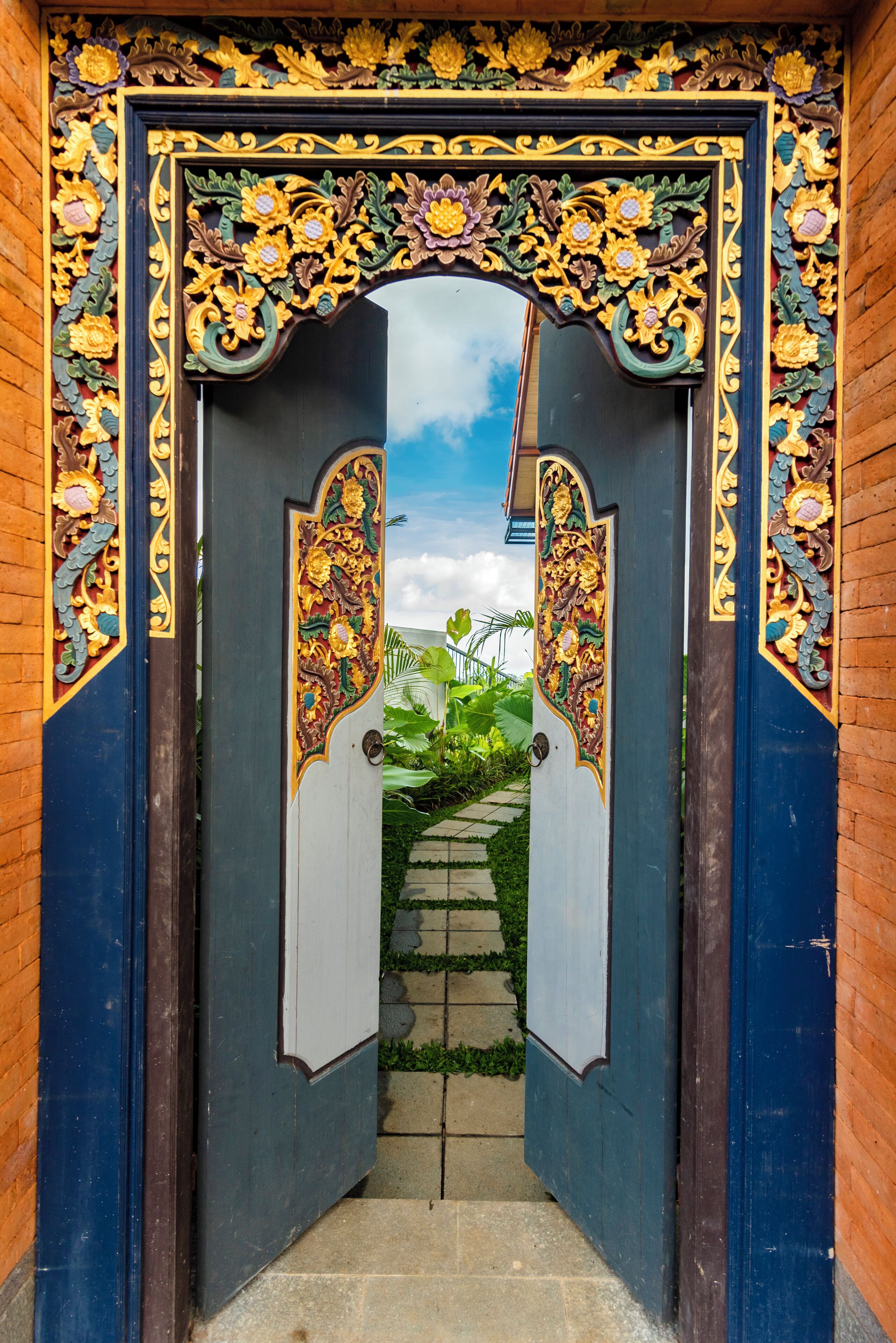 An ornate gate with intricate floral carvings, leading to a pathway.