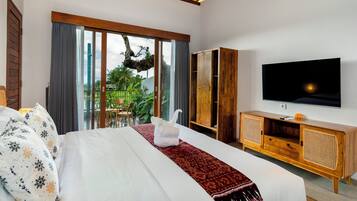 Een moderne hotelkamer met een groot bed, een televisie, een houten kastje en uitzicht op groen buiten het raam.