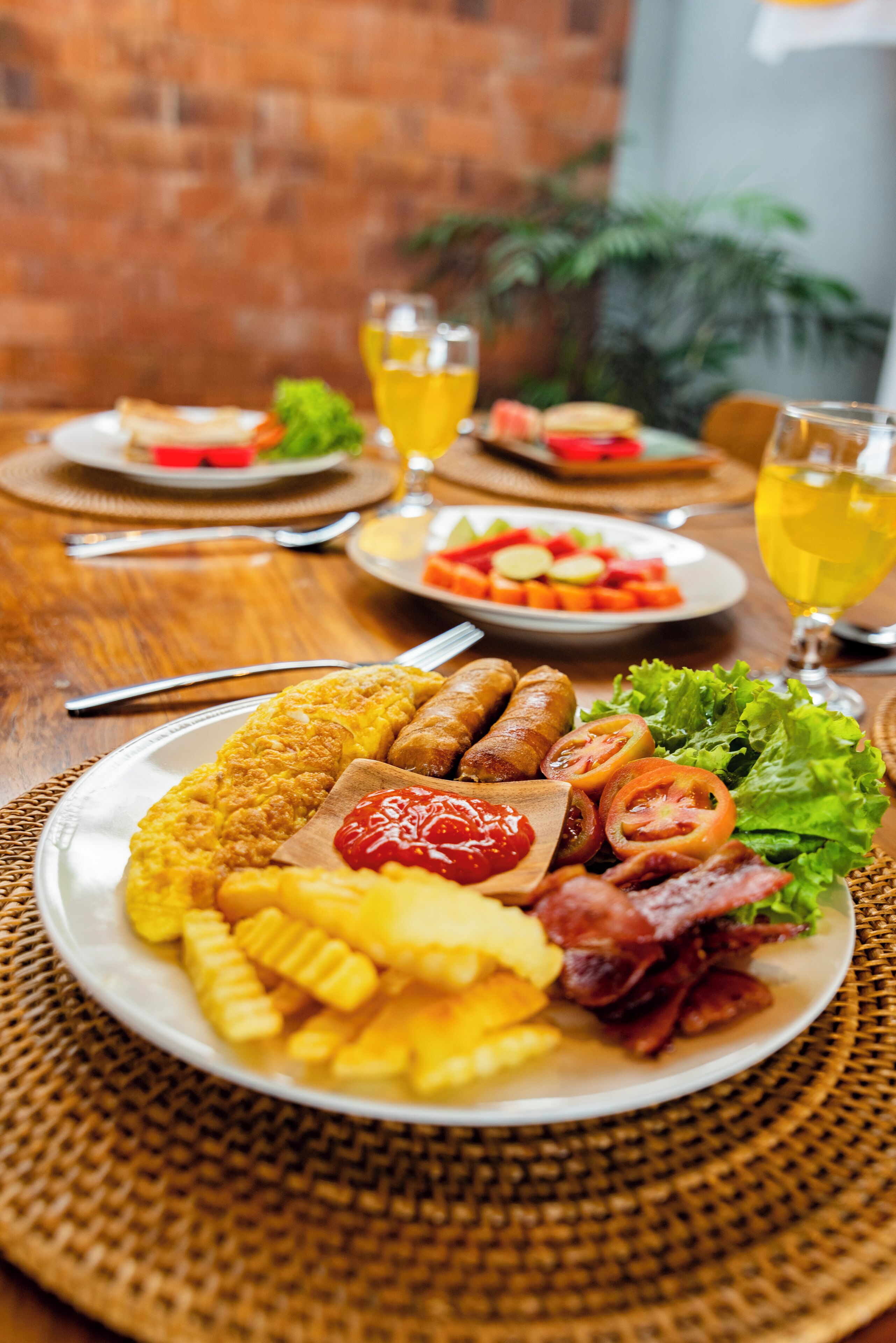 Een gedekte tafel met borden eten, waaronder worstjes, friet en een salade, met drankjes in glazen.