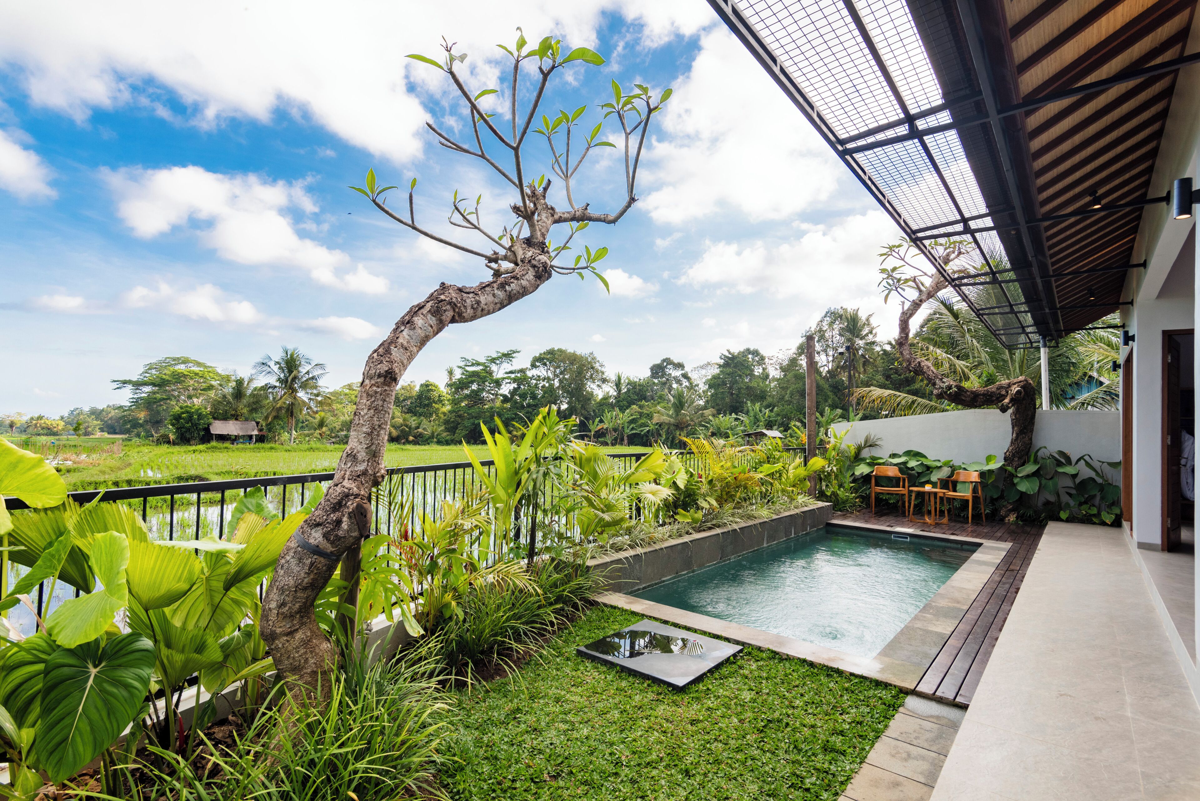 A swimming pool with a surrounding garden, a wooden deck, and a view of the countryside.