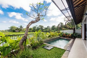 Una piscina con un jardín a su alrededor, una terraza de madera y vistas al campo.