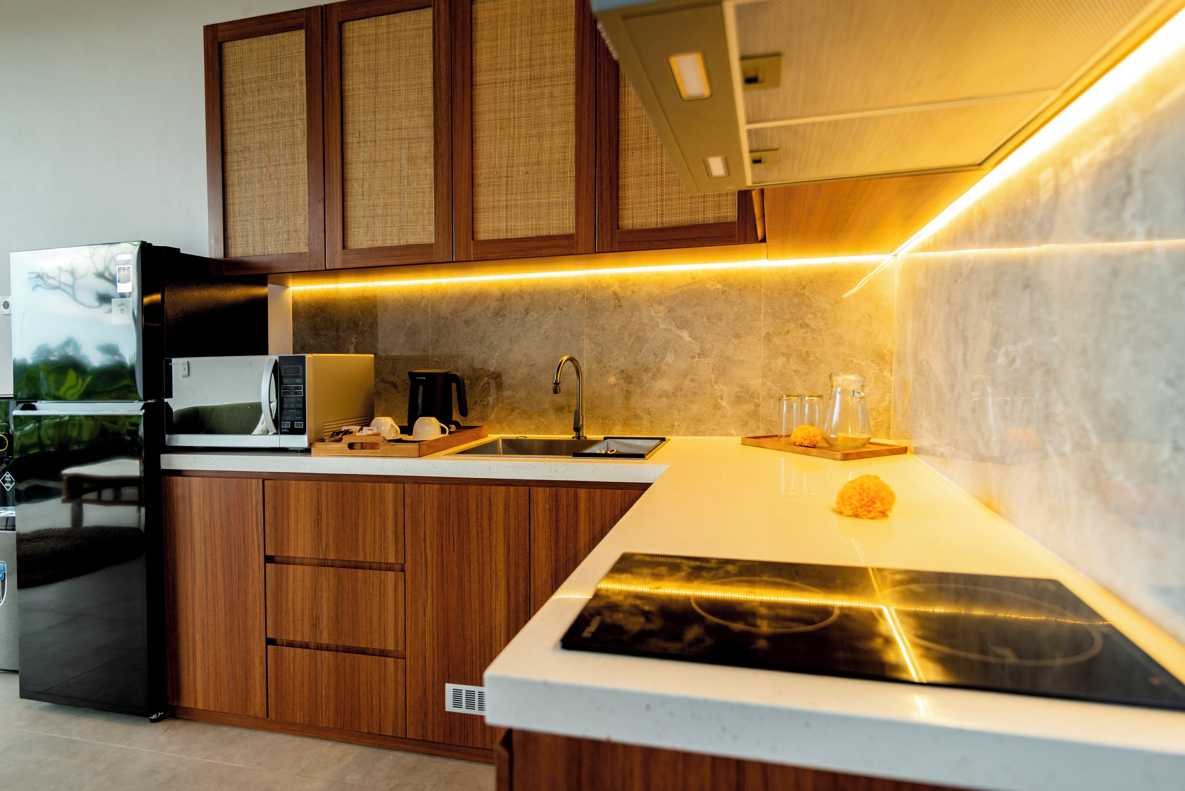 A modern kitchen with wooden cabinets, a built-in microwave, a coffee maker, and a sink.