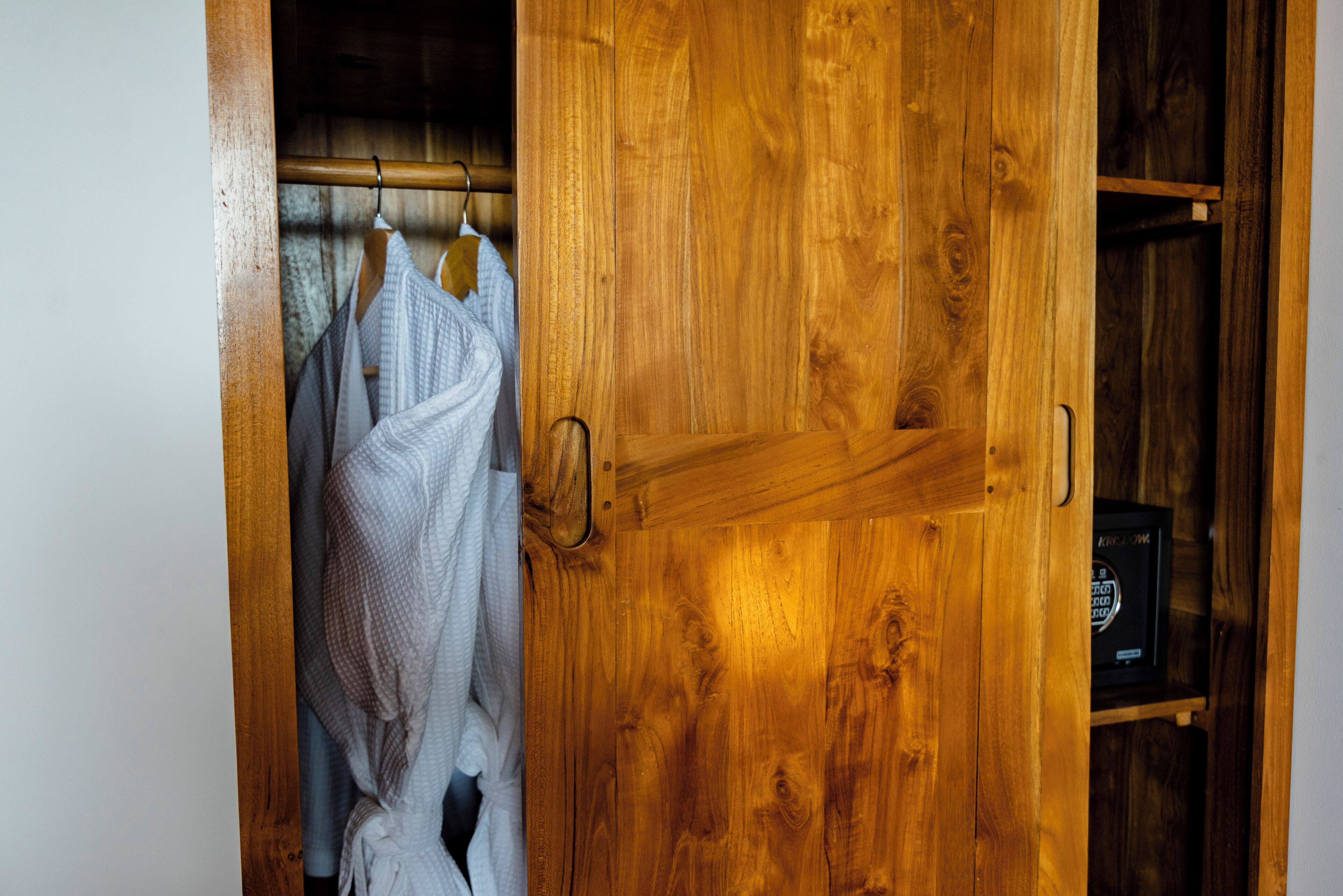 Un armario de madera con una barra para colgar y un estante pequeño.