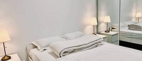 A hotel room with a bed, nightstands, lamps, and a mirror.