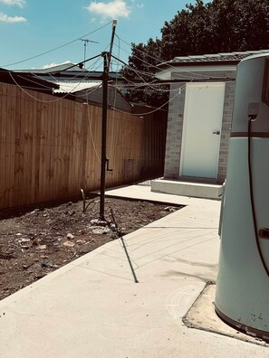 A residential backyard with a wooden fence, a concrete pathway, and a utility meter. - New 2BR1B Flat+2 Free parking|Lake nearby&Hospital (North Parramatta)