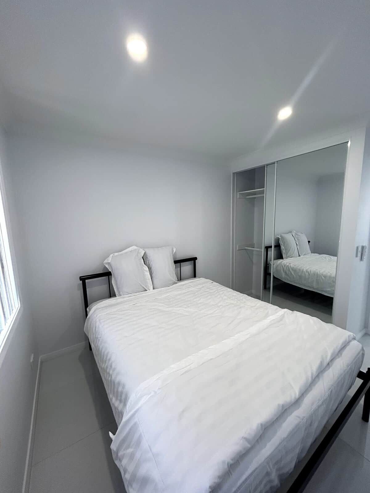 A bedroom with a bed, a wardrobe, and a mirror.