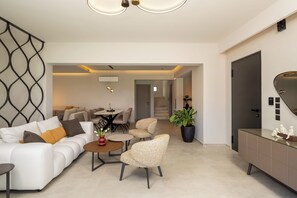 Una sala de estar moderna con un sofá, sillas, una mesa de centro y un comedor.