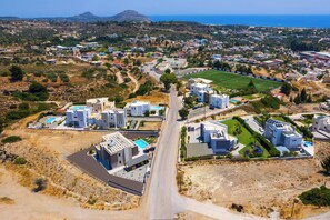 Zona residencial amb edificis moderns, un carrer i un camp esportiu.