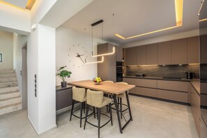Una cocina moderna con una mesa de madera, cuatro sillas y una planta en maceta.