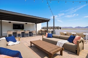 An outdoor patio with a sofa, chairs, a table, and a grill area. - Desert Ridge Condo • Shared Rooftop Pool + Sauna + Mountain Views | Azur #245 (Phoenix)