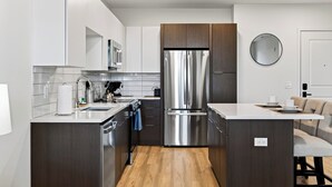 A modern kitchen with stainless steel appliances, a wooden countertop, and a built-in oven. - Desert Ridge Condo • Shared Rooftop Pool + Sauna + Mountain Views | Azur #245 (Phoenix)