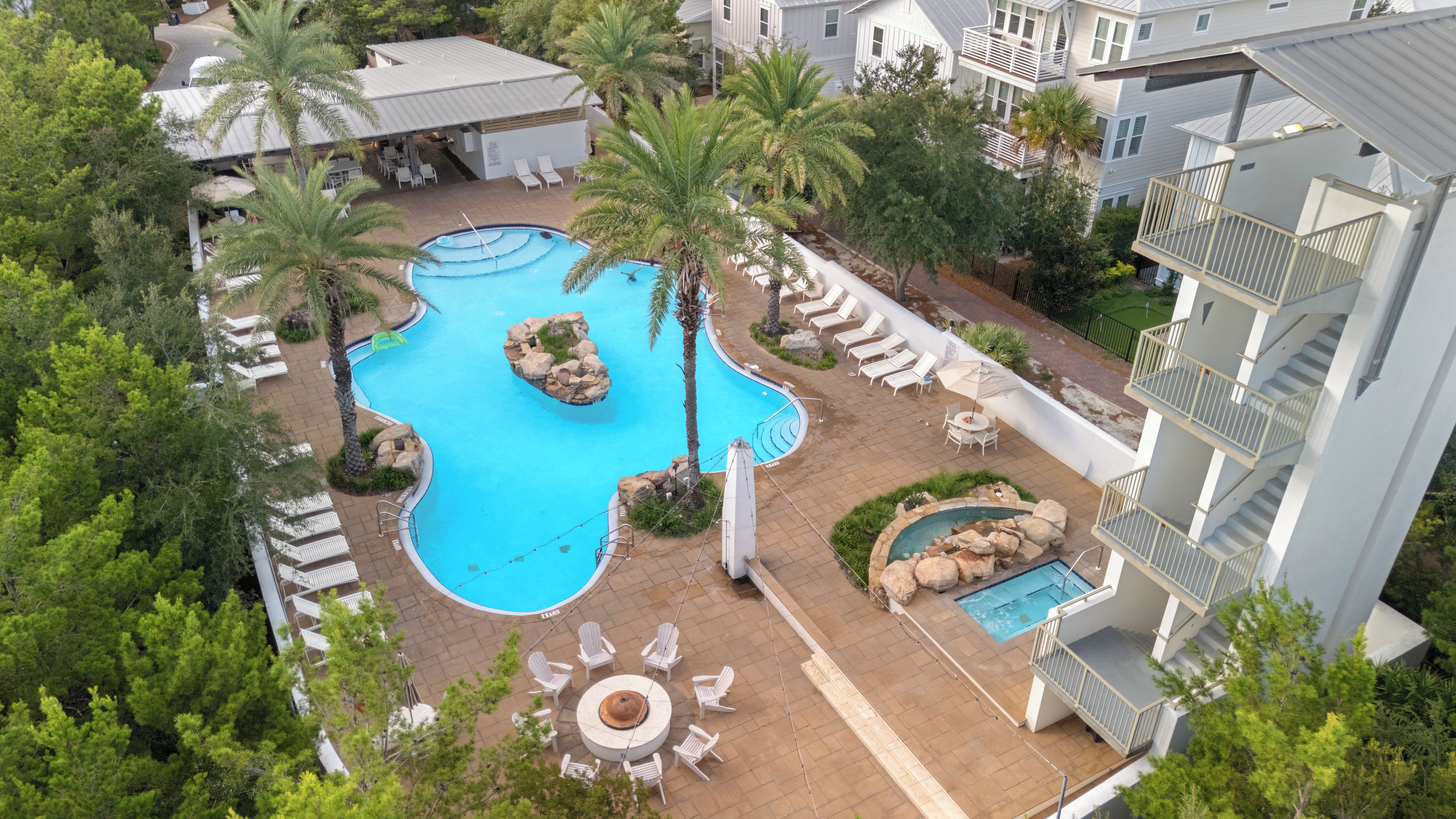 Un hôtel à plusieurs étages doté d’une piscine centrale, d’un espace extérieur aménagé et de palmiers.