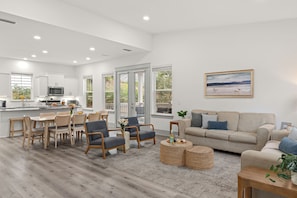A modern living room with a sofa, chairs, a coffee table, and a dining area with a table and chairs. - Golf Cart + Hot Tub + Community Pool | Near the Gulf | 78 Emerald (Santa Rosa Beach)