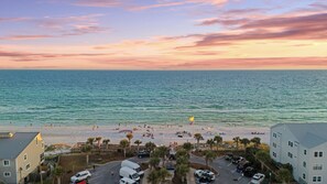 A beach view with a parking area, buildings, and a clear sky. - Golf Cart + Hot Tub + Community Pool | Near the Gulf | 78 Emerald (Santa Rosa Beach)