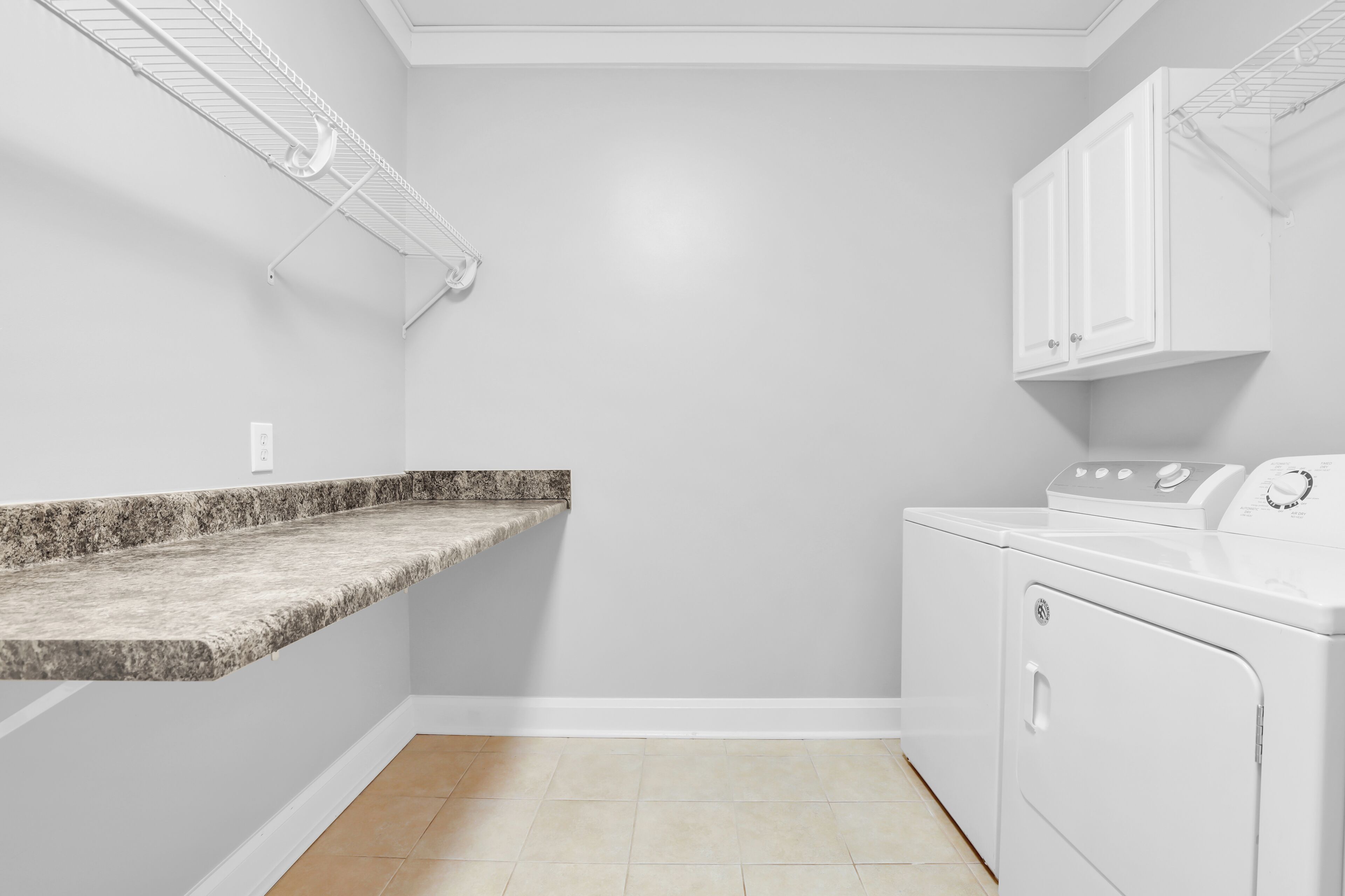 A laundry room with a granite countertop, a washing machine, and a drying rack.