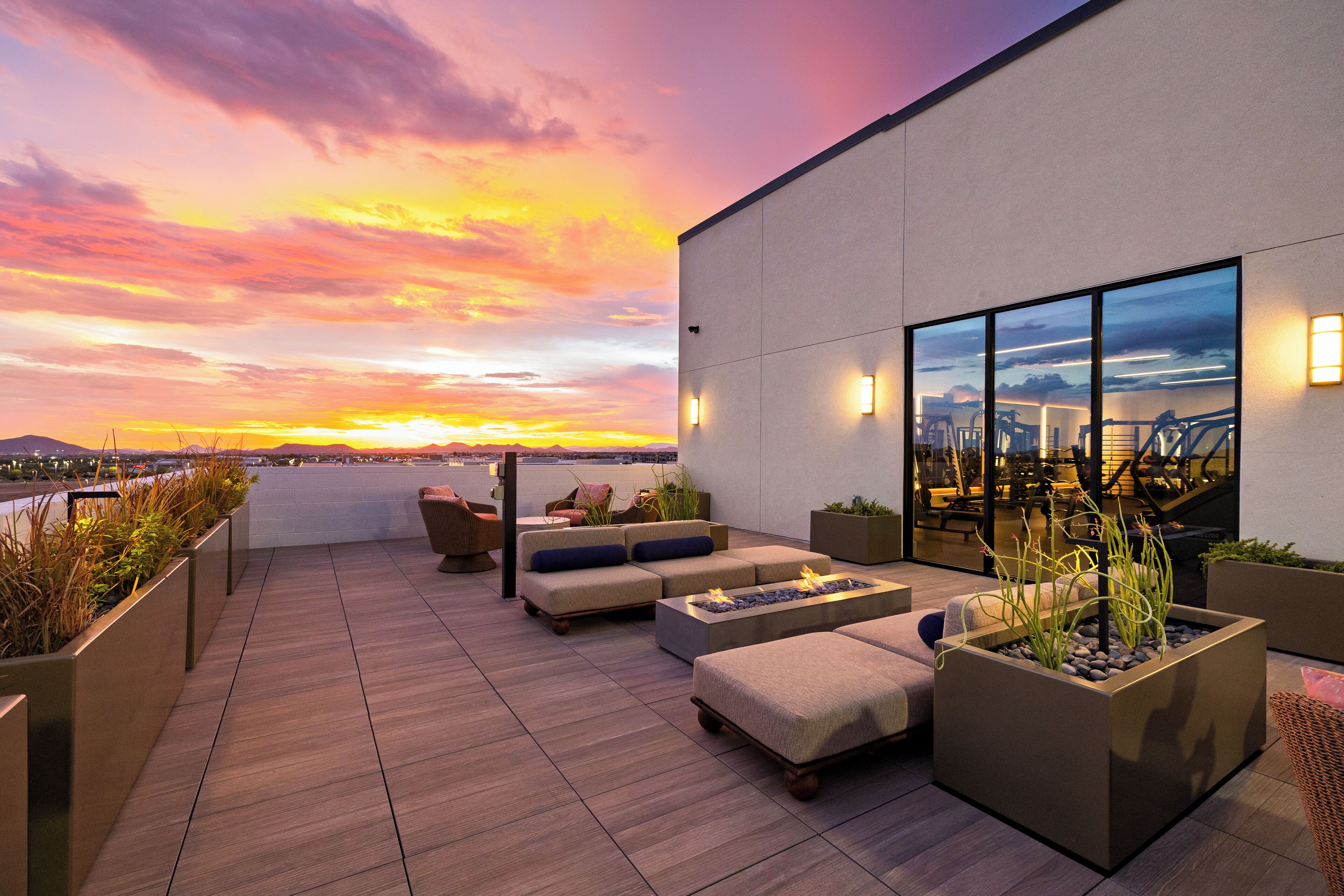 Terraza en la azotea con asientos, una chimenea y vistas al atardecer sobre la ciudad.