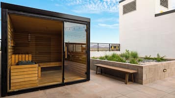Een moderne buitenruimte met een houten bank, een sauna en uitzicht op de stad.