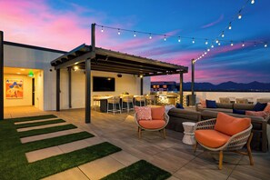 Eine Außenpatio-Terrasse mit einer Pergola, Sitzgelegenheiten und einer Bar.