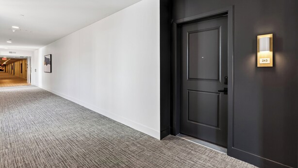 A hallway with a dark door, a light switch, and a number plate. - Rooftop Pool + Sauna & Spa | Near TPC Golf + Preserve | Azur (Phoenix)