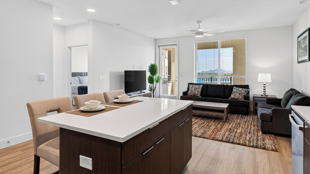A modern apartment with a kitchen island, dining area, living room, and a balcony with a view. - Rooftop Pool + Sauna & Spa | Mins to Desert Ridge + TPC Golf | Azur (Phoenix)