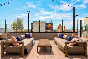 Ein Außenbereich mit Sofas und einem Tisch mit Blick auf eine Stadtlandschaft.